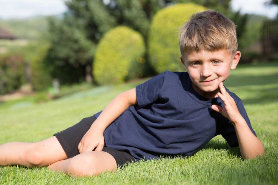 Portrait of a boy lying on the lawn on his side, smiling